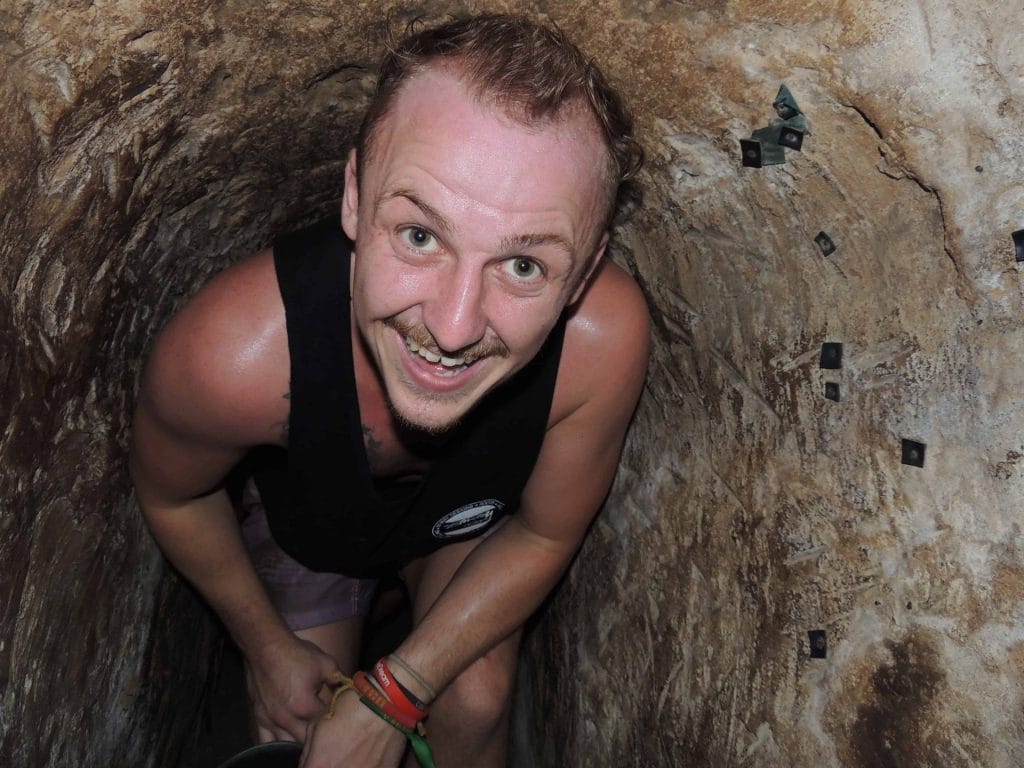 Man crouching through Cu Chi Tunnels in Ho Chi Min, Vietnam