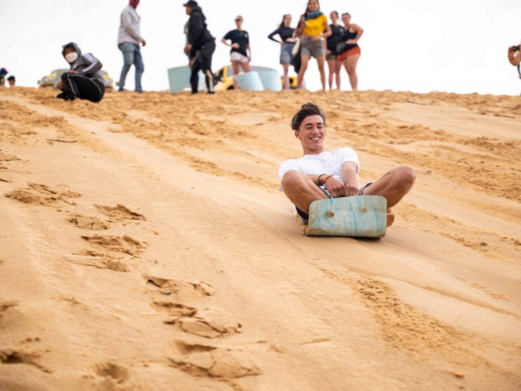 Man sliding down the sand dunes on a sandboard