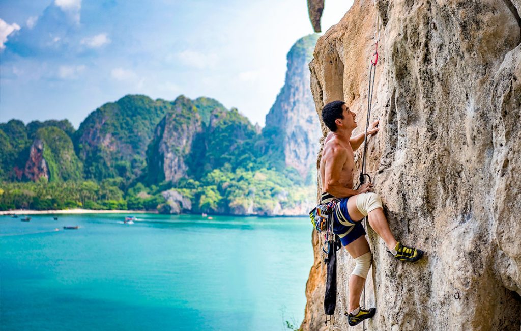 A man climbing up a limestone cliff on one of Thailand's islands.