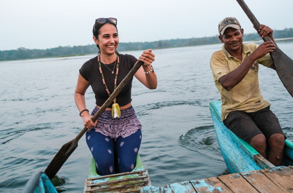 A woman joyfully paddling a canoe with a local guide on a tranquil river, capturing the essence of local travel experiences. Taking a lake safari is one of the best things to do in Sigiriya.