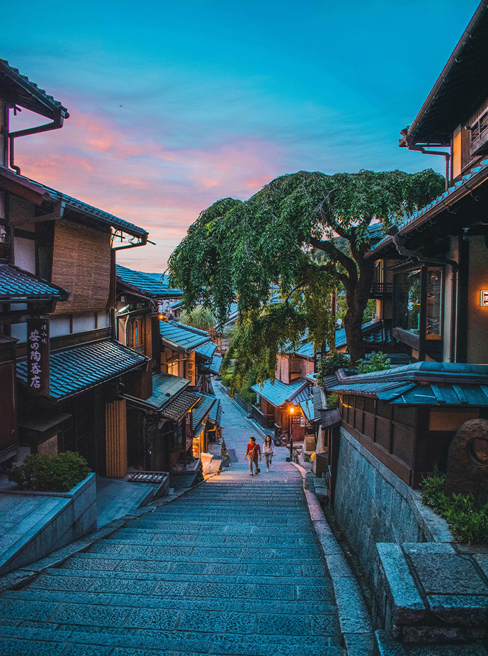 Traditional streets of Kyoto’s Higashiyama district glow at dusk with stone steps and wooden houses.