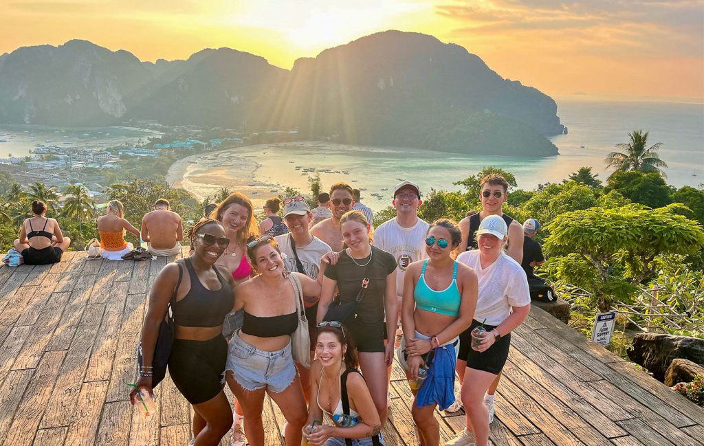 A travel group posing for a photo in front of the sunset in thailand