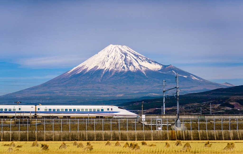 A Shinkansen bullet train speeds past with Mount Fuji towering in the background.