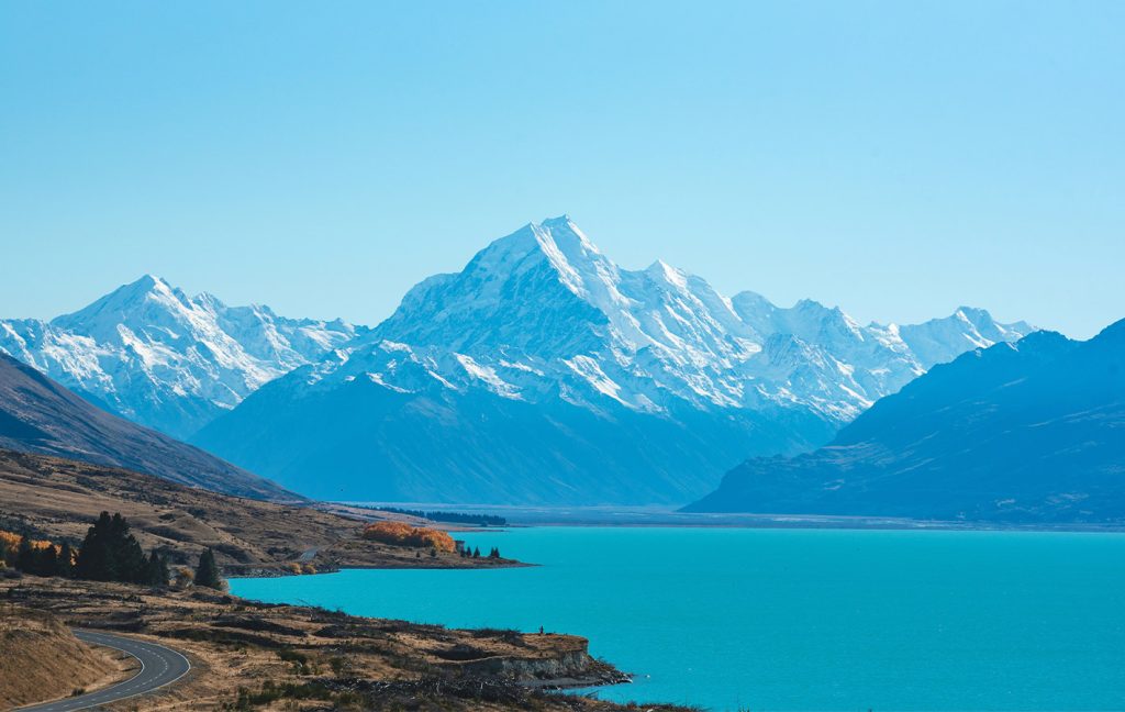 Snow-capped mountains reflect in the turquoise waters of a peaceful lake.