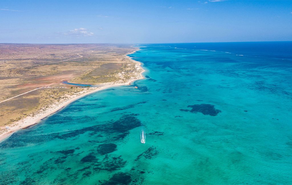 The endless turquoise coastline of Ningaloo Reef stretching along the horizon.