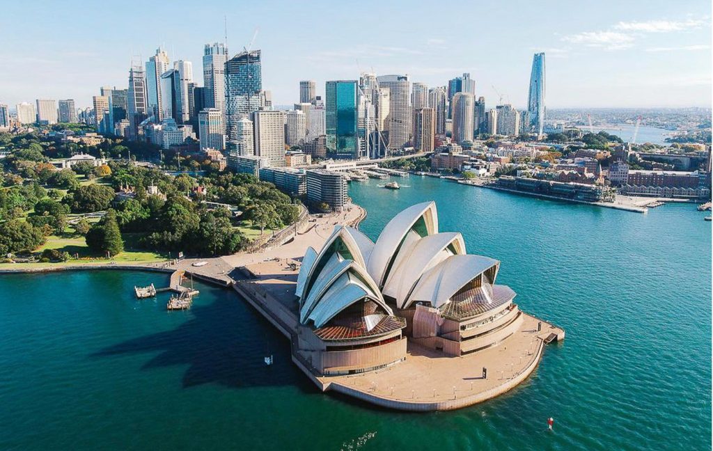 Sydney’s iconic Opera House with the city skyline rising behind it.